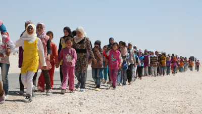   Syrian children march in the refugee camp in Jordan.  The number of Children in this camp exceeds 60% of the total number of refugees hence the name "Children's camp". Some of them lost their relatives, but others lost their parents.